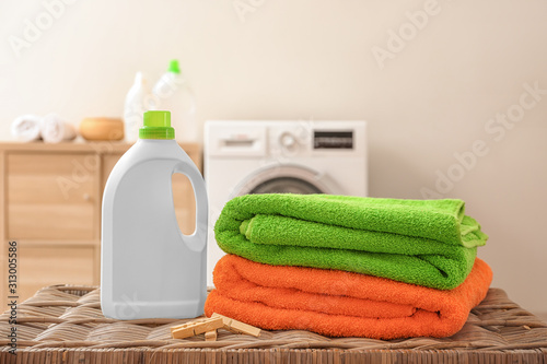 Clean laundry and washing liquid on table in bathroom