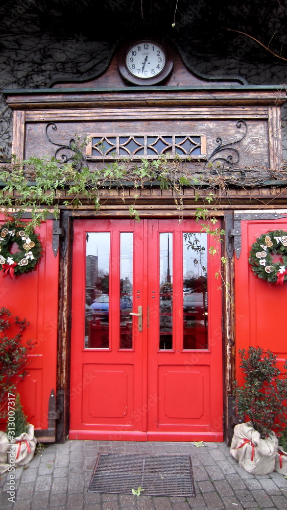 Red large wooden door with a clock above the entrance Red large wooden door with a clock above the entrance