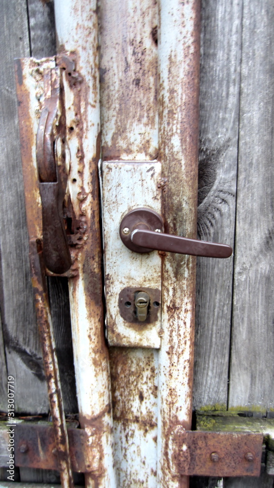 Handle and rusty lock in wooden wicket door close-up Handle and rusty lock in wooden wicket door close-up