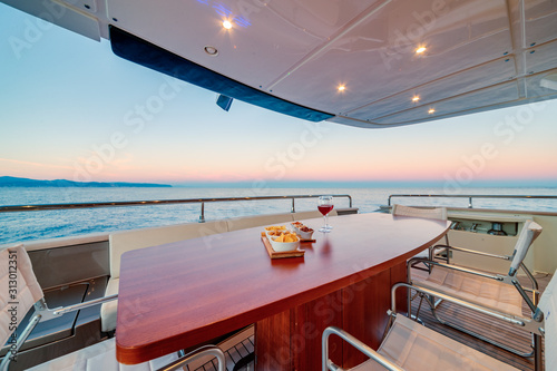 Beautiful shot from the yacht of a wooden table with wine glasses at sunset