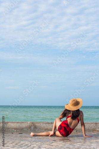 Young attractive woman sitting on a pier enjoying the view looking the sea