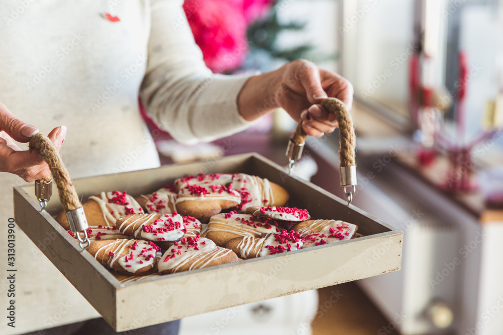 Young womans hands hold big box with hommade cookies hearts. Present for Valentines day