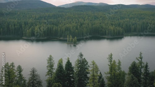 Aerial: Flying over an island on a calm lake and forest at autumn time. Seeley Lake, Montana, USA photo