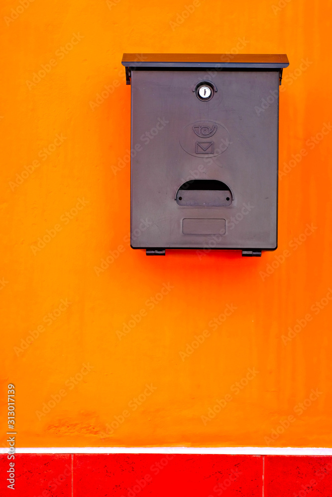 A black letter box on a vibrant orange background. A black letter box on a vibrant orange background.