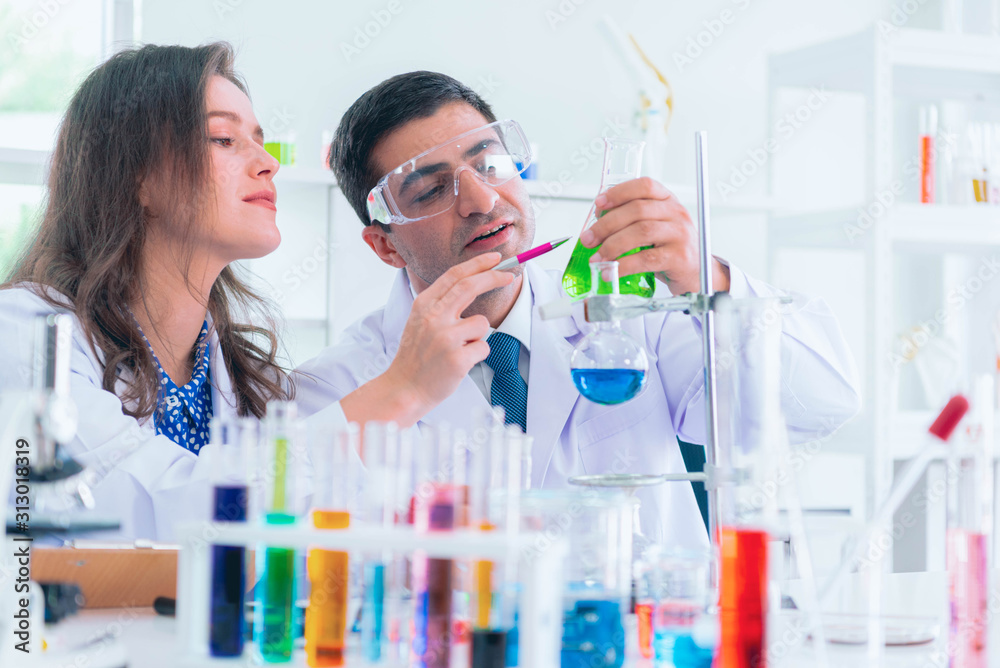 Two scientists are working in laboratory. Young female and male researcher are doing investigations with test tubes. Two scientists are working in laboratory. Young female and male researcher are doing investigations with test tubes.