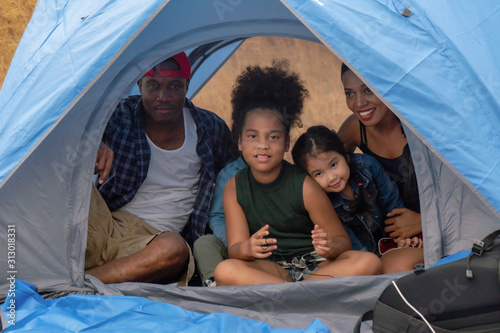 african american family, parent with kids, and asian adoped child having fun together in camping at natural park