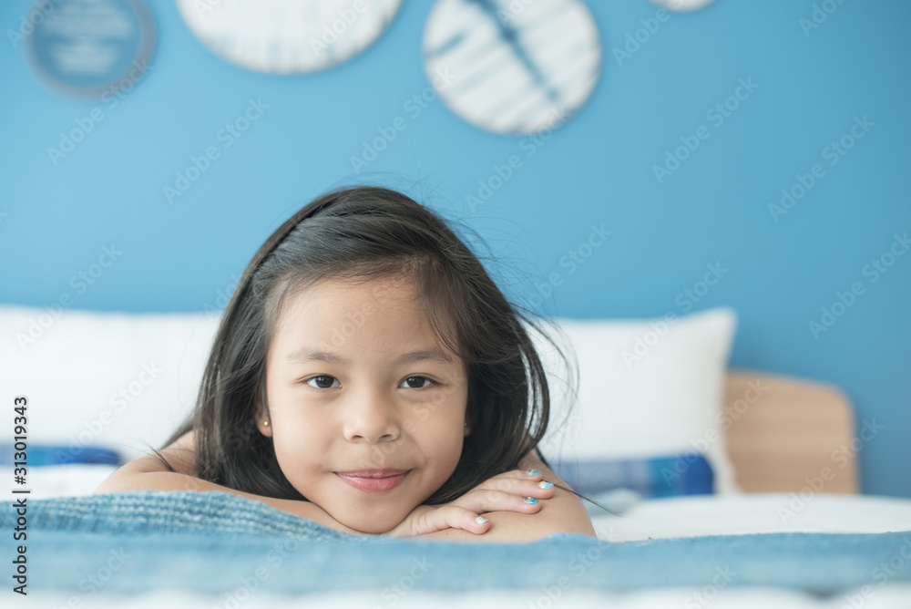 adorable little child girl sleeping in the bed. a nice child girl enjoys sunny morning. good morning at home. child girl wakes up from sleep. health and beauty concept - obrazy, fototapety, plakaty 
