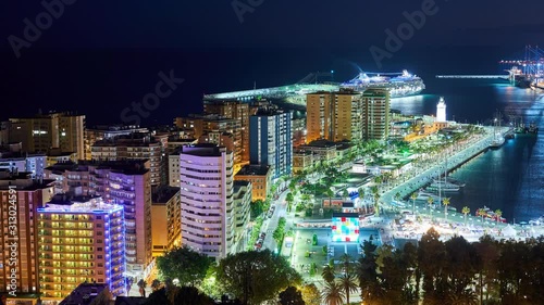 night timelapse of the historic harbor of Malaga with busy people and illuminations. Costa del Sol, Spain photo
