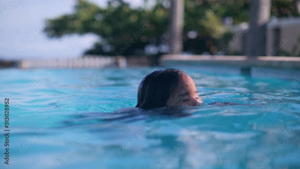 Young asian girl diving underwater and swimming in pool in tropics on vacations. Young asian girl diving underwater and swimming in pool in tropics on vacations.