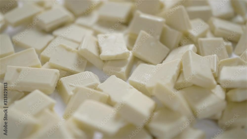 cube of white milk chocolate is being taken from table full of cubs milk white chocolate on a white background cube of white milk chocolate is being taken from table full of cubs milk white chocolate on a white background