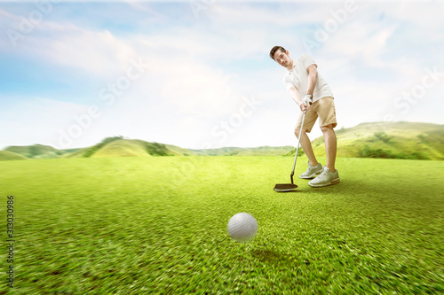 Asian man swing the golf club and hitting the ball