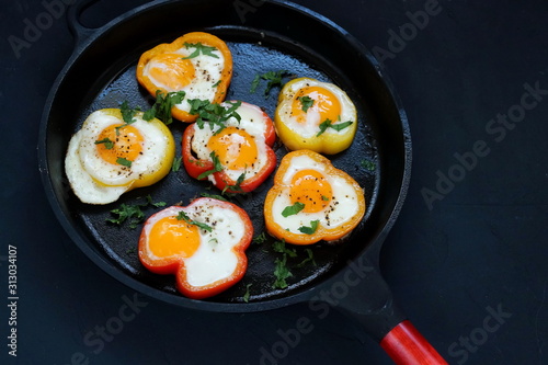 healthy breakfast food. red bell peppers stuffed with eggs close up  in a cast-iron pan