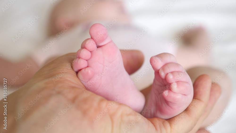 Newborn Baby Feet In Father Hands. Close-Up. Newborn Baby Feet In Father Hands. Close-Up.