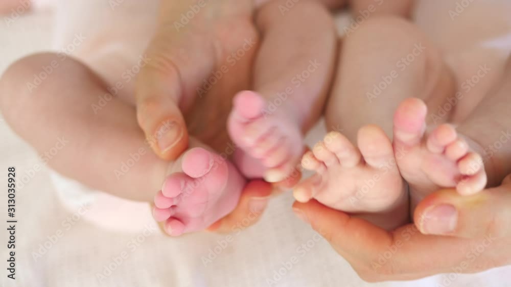 Newborn Baby Feet Of Twins In Mother's Hands. Newborn Baby Feet Of Twins In Mother's Hands.