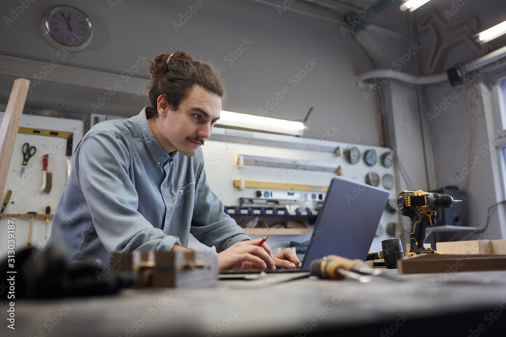 custom made wallpaper toronto digitalYoung repairman working online he typing on laptop computer at the table in workshop