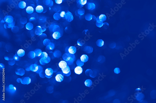 Abstract bright sparkling background, defocused christmas lights. Blurred background for holidays and parties in blue colors. Color of the year 2020.