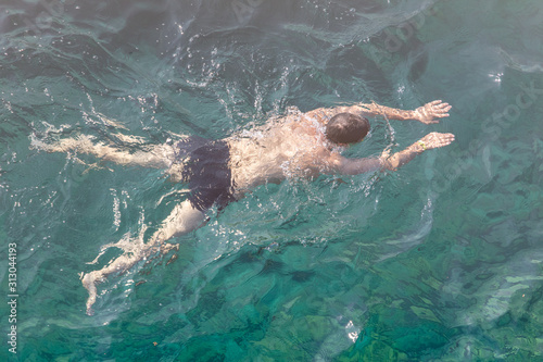 A man swims in the blue water of the sea
