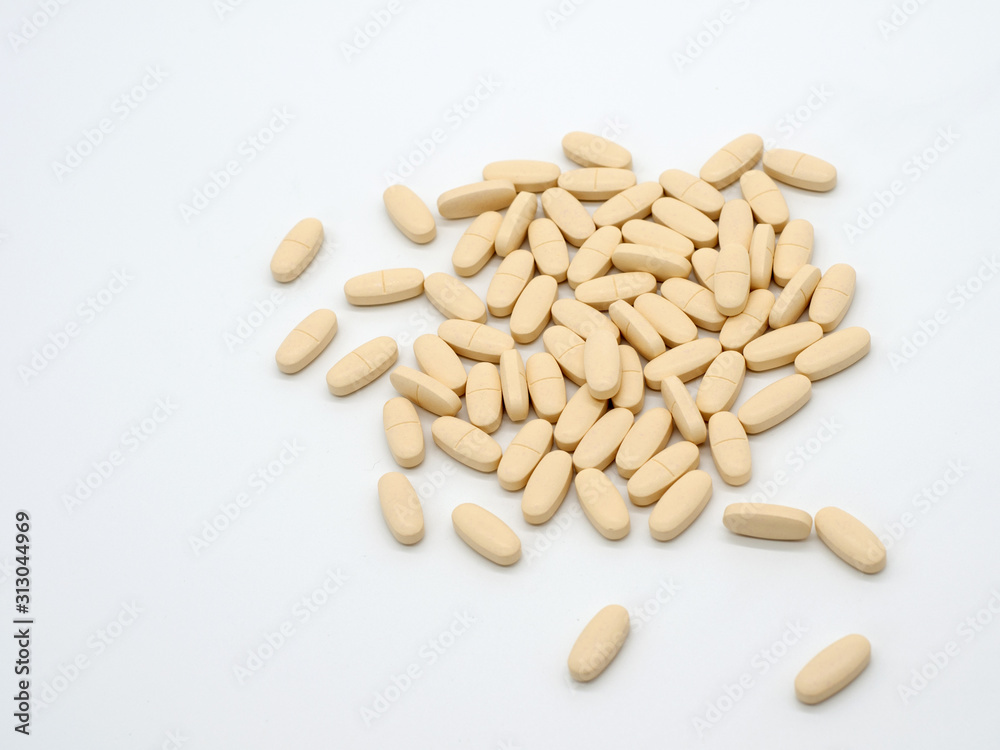 Light colored tablets are scattered on a white background. Selective focus Light colored tablets are scattered on a white background. Selective focus