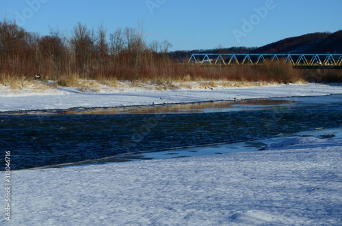 winter landscape in the forest with snow and blue sky and river