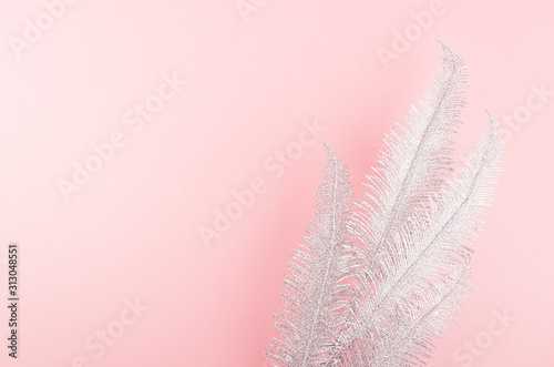 Fashion festive background of silver feathers on pastel pink backdrop, top view, copy space. © finepoints