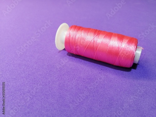 new spool of silk pink threads on a lilac background