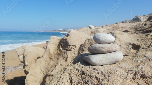 pyramid of white stones on a rocky shore  blue sea  blue sky
