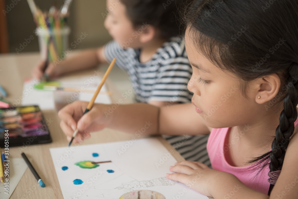 group little girl with brush painting on table in School, education, cut girl painting in at her home. Selective focus and small depth of field, Painting with watercolor, drawing, Creativity concept. group little girl with brush painting on table in School, education, cut girl painting in at her home. Selective focus and small depth of field, Painting with watercolor, drawing, Creativity concept.