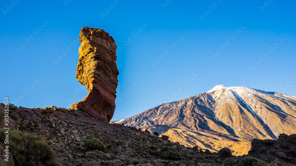 Spain, Tenerife, Famous eroded rocks called roques de garcia with view to summit of volcano mountain teide with white snow at sunset