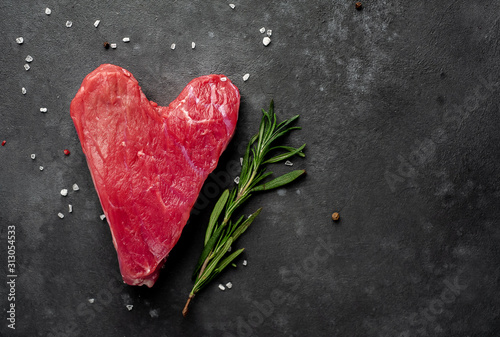 heart shaped raw beef steak with spices for valentines day on stone background with copy space for your text  concept of cooking dinner for valentines day