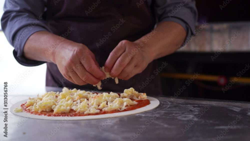 Chef putting ingredient on pizza dough Chef putting ingredient on pizza dough