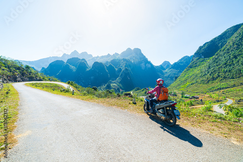 One person riding bike on Ha Giang motorbike loop, famous travel destination bikers easy riders. Ha Giang karst geopark mountain landscape in North Vietnam. Winding road in stunning scenery.