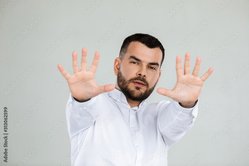 handsome bearded man showing stop gesture on gray background. handsome bearded man showing stop gesture on gray background.