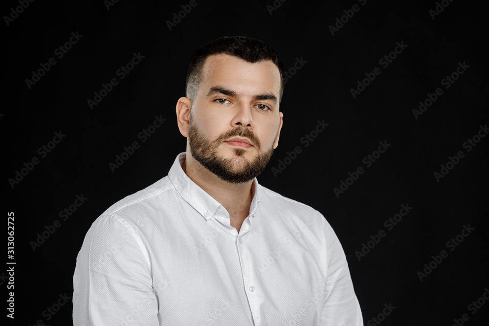 calm handsome bearded man poses in studio on black background