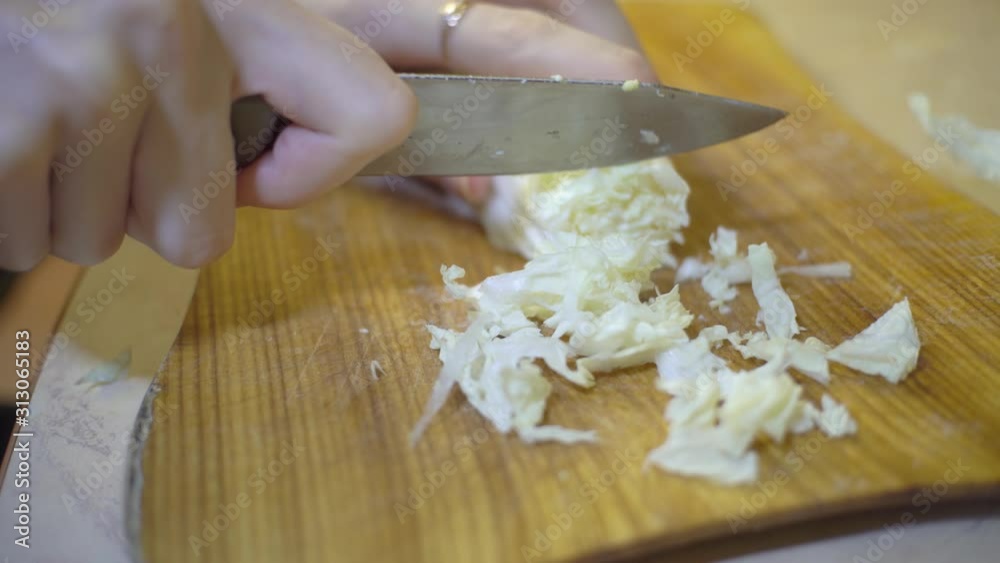 Close up chef cuts chinese chinese cabbage on a wooden cutting board, cooking healthy food. Close up chef cuts chinese chinese cabbage on a wooden cutting board, cooking healthy food.