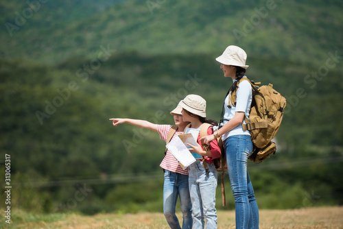The three siblings stood on the road, pointing their hands forward. With a backpack and a hat in the countryside. She enjoys traveling in the summer. Travel and adventure concepts