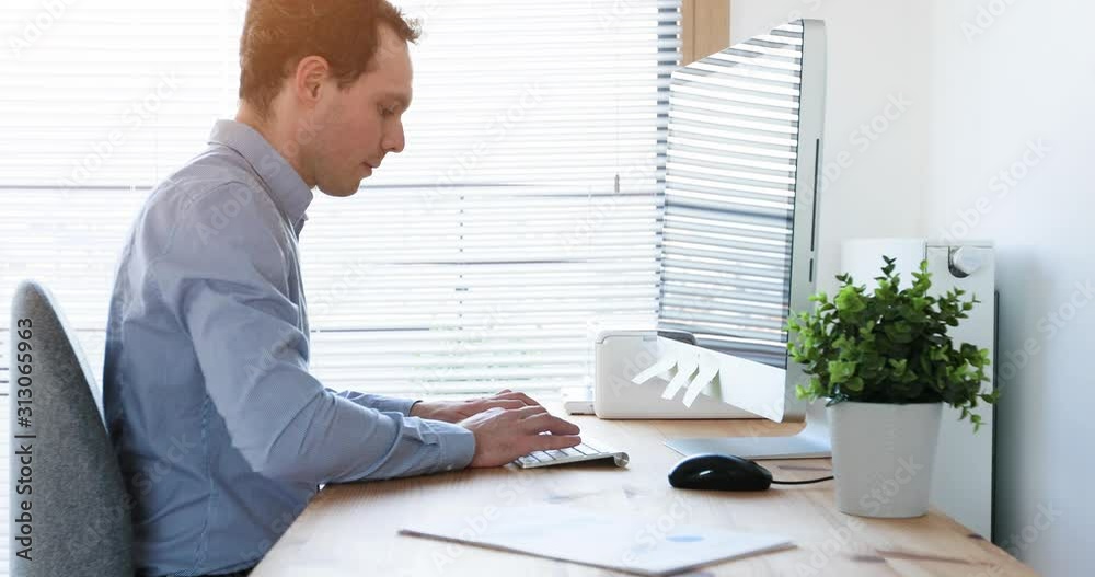 Employee working on computer in sunny bright modern office workplace, business person typing on keyboard and watching screen, management, accounting or financial concept, 4K video footage, dolly shot