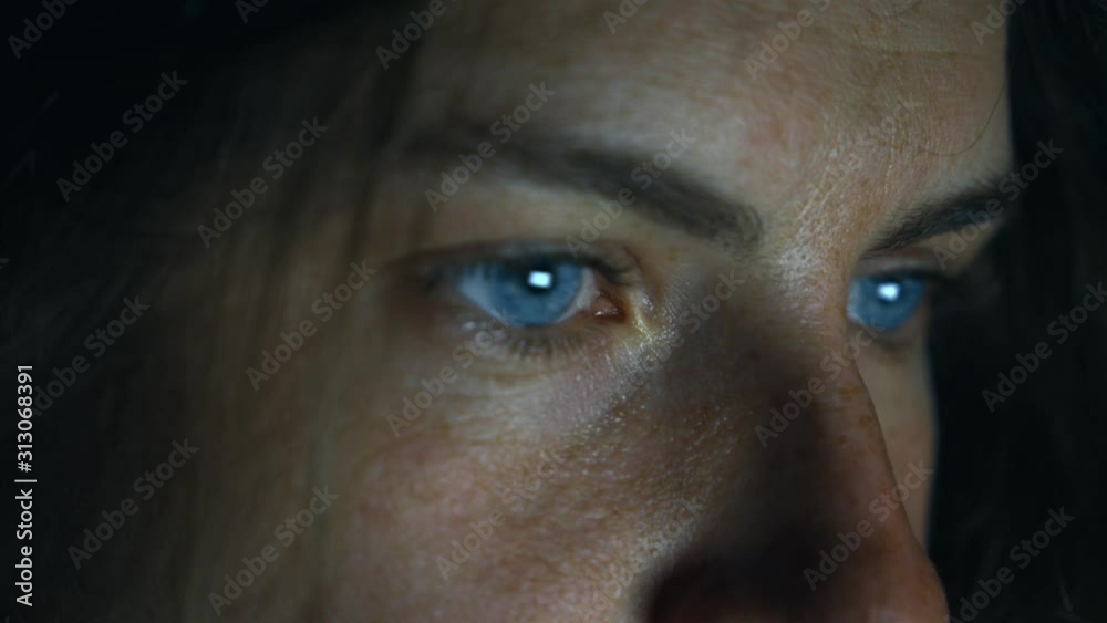 Female face in darkness, screen eye reflection Female face in darkness, screen eye reflection