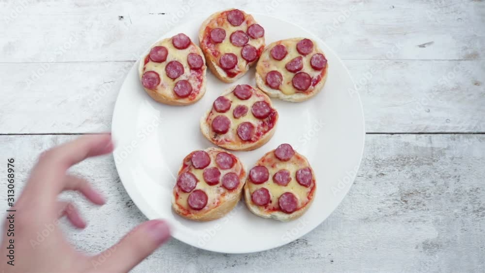 man hand takes mini pizza sandwich from white plate close up man hand takes mini pizza sandwich from white plate close up