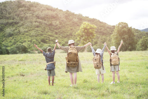 Happy asian woman girl and children goes to summer travel trip with mountain background. They stood, turned their backs and raised their hands to breathe fresh air. Travel and adventure concept.