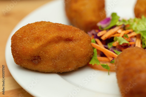 Close-up of a croquette with salad on a plate