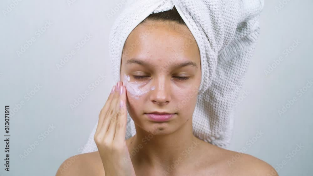 Teen girl applying face cream after bath in the morning Teen girl applying face cream after bath in the morning