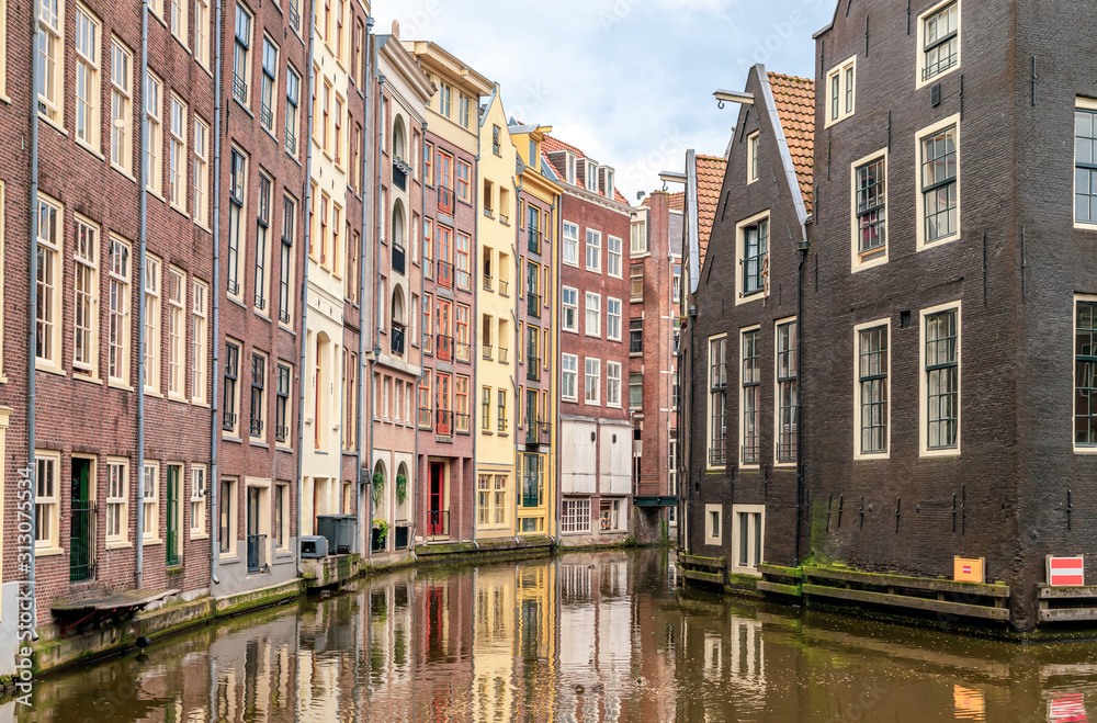 Row of typical colourful dutch houses reflected in water on Amsterdam canal. Amsterdam, Netherlands.