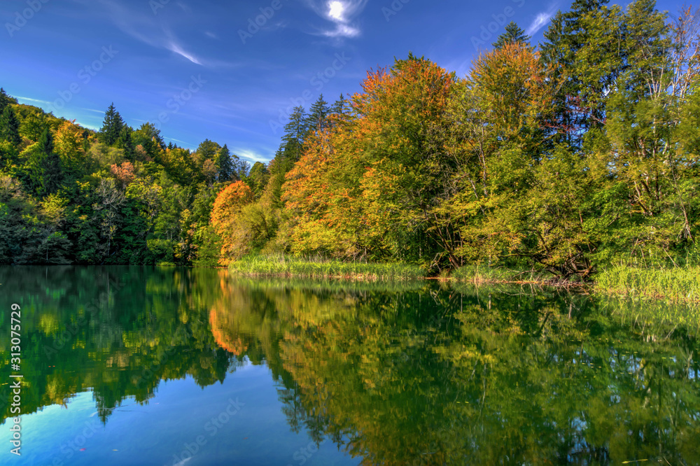 Reflection of the autumn forest in the lake. Mirror reflection of trees and sky in the lake. Autumn landscape. Reflection of the autumn forest in the lake. Mirror reflection of trees and sky in the lake. Autumn landscape.
