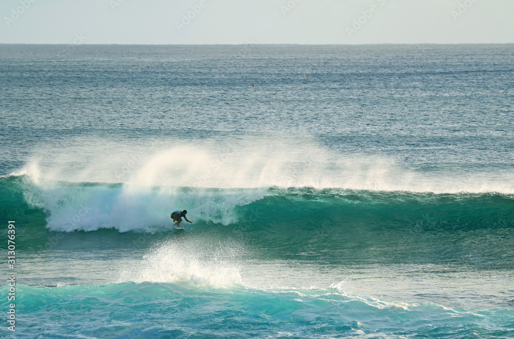 Young surfer riding on the breaking waves in Pacific Ocean at Hanga Roa, Easter Island, Chile	