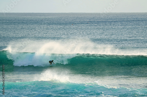 Young surfer riding on the breaking waves in Pacific Ocean at Hanga Roa, Easter Island, Chile 