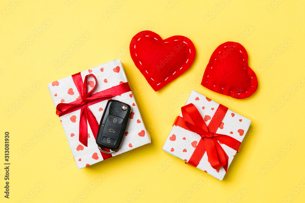 Top view of car key on gift box and red textile hearts on colorful background. Present for Valentine's Day concept Top view of car key on gift box and red textile hearts on colorful background. Present for Valentine's Day concept