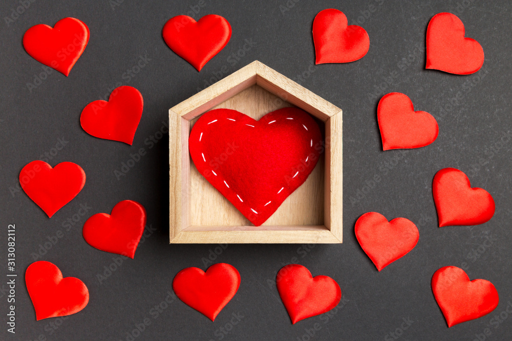 Close up of red heart in a wooden house decorated with small hearts on colorful background. Valentine's day. Home sweet home concept