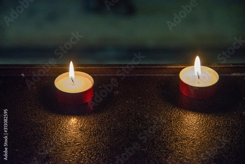 Close up of two votive candles in a church. Candles in the dark with flames on red copper supports. photo