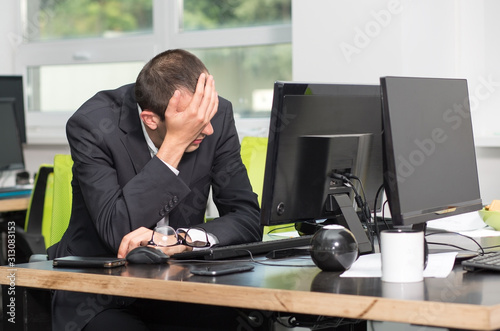 Sad businessman sitting in front of monitor computer in the office. Stressed work.