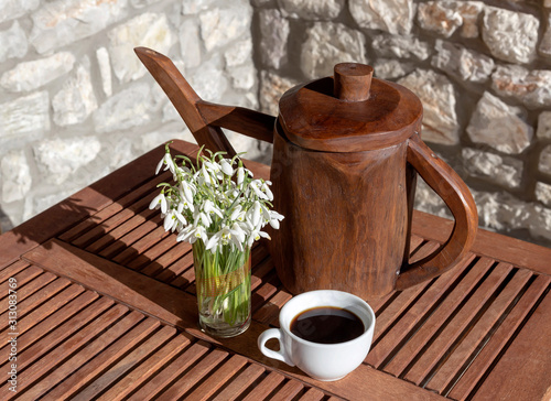 ouquet of snowdrops and coffee in a cup on the balcony photo